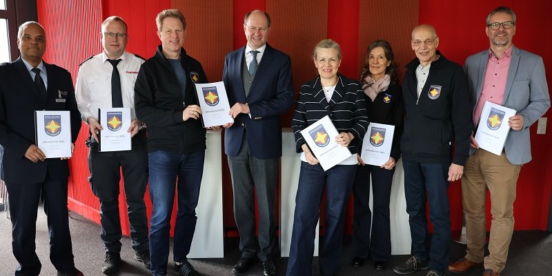 Johannes Schütze (Kreispolizeibehörde Warendorf Direktion Gefahrenabwehr/Einsatz, v. l.), Nils Recker (stv. Leiter der Kreisleitstelle), Martin Remke (Koordinator für die Notfallseelsorge im Kreis Warendorf), Landrat Dr. Olaf Gericke, Ordnungsdezernentin Petra Schreier, Petra Huß (Notfallseelsorgerin), Martin Kofoth (Feuerwehrseelsorger) und Michael Frerich (Amtsleiter Bevölkerungsschutz) bei der Übergabe des Jahresberichts. 		Foto: Kreis Warendorf