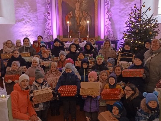 Die beschenkten Familien versammelten in der Ev. Kirche in Matiši zusammen mit der Leiterin der Sonntagsschule Kristine Daiga (vorne links), Kirchenvorstand Sandra Kruzkope und Pastor Raitis Jakobsons (beide hinten links). 		Foto: privat