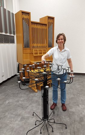 Pfarrerin Elisabeth Biermann hat die Umgestaltung der Gefängniskapelle wesentlich mitgestaltet. Der Kerzenbaum wurde in der anstaltseigenen Schlosserei hergestellt. Er bietet in den Gottesdiensten, die sie und ihre Kolleg:innen dort gestalten, den Gottesdienstbesuchern die Möglichkeit, fürbittend Kerzen anzuzünden. 		Foto: fra